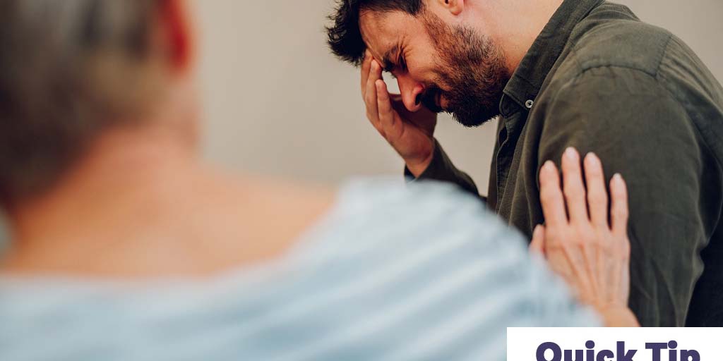 A man shows emotion or pain while a woman supports him.