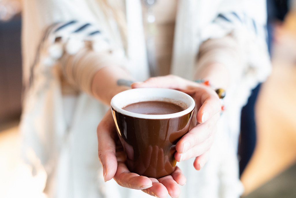 A woman offers a cup of hot chocolate.