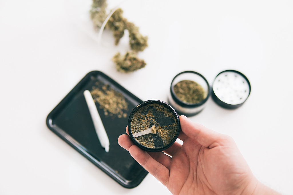 Kief in a grinder with a rolling tray and joint in the background.