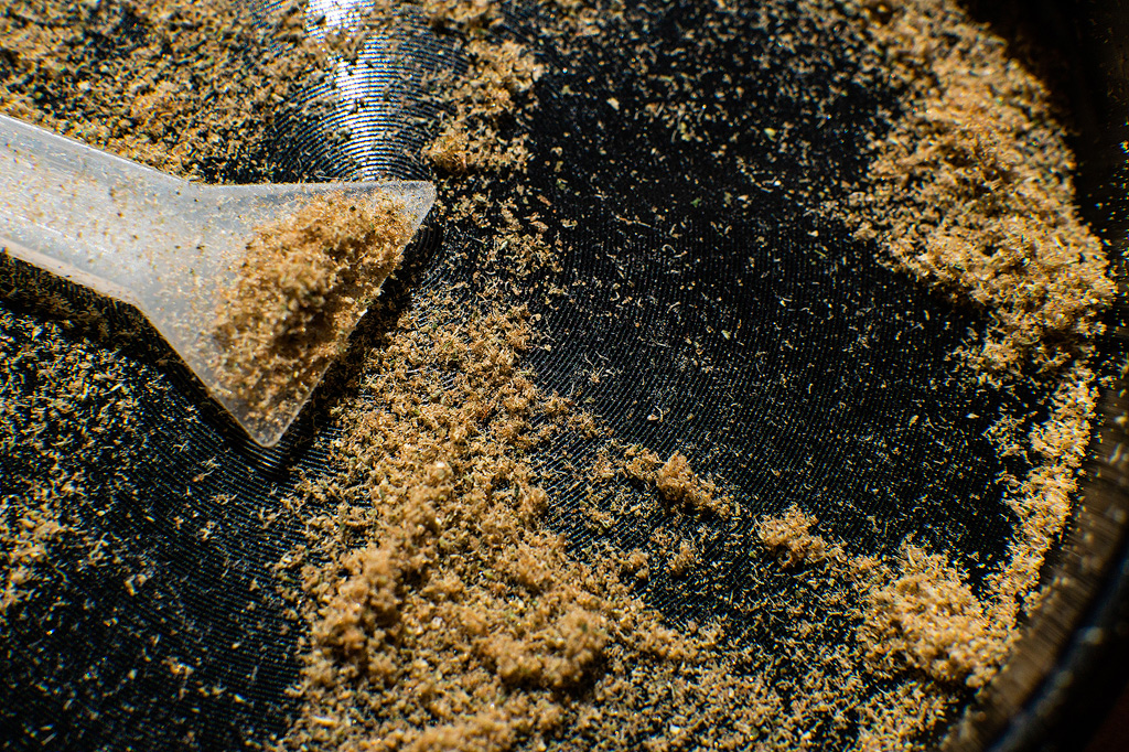 Kief at the bottom of a grinder with a scraper.