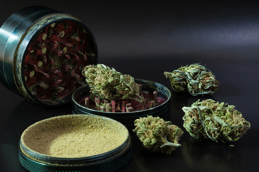 A grinder with cannabis buds and a compartment filled with kief.